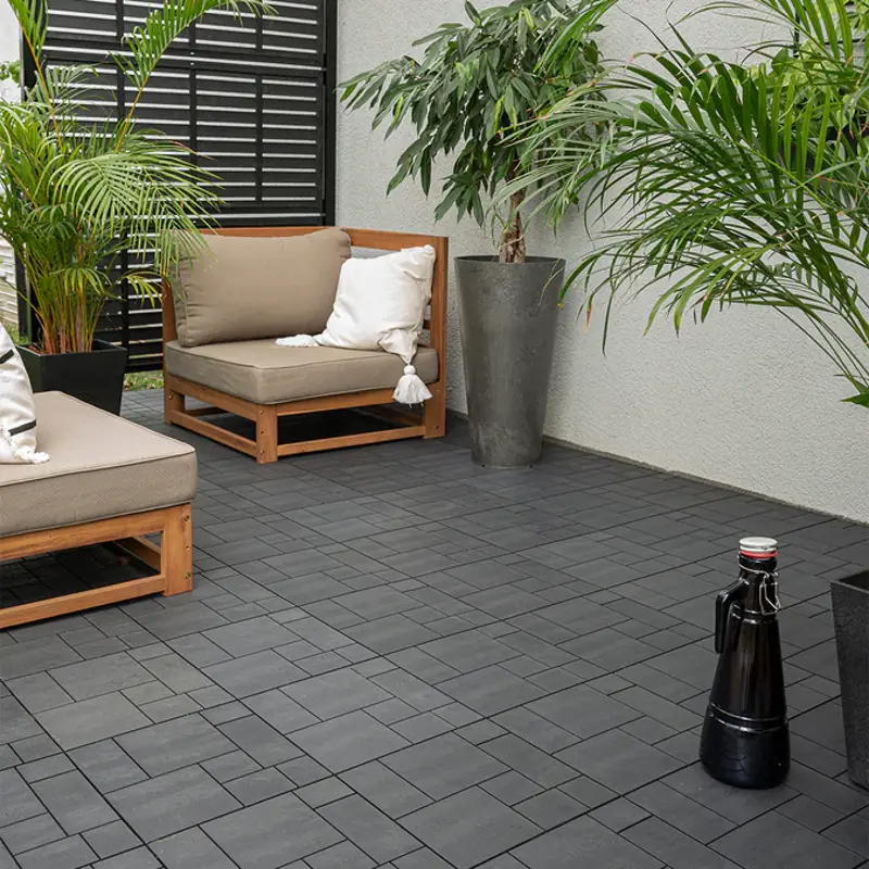Black interlocking deck tiles with patio furniture and plants.