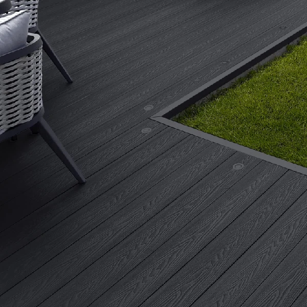 Dark composite decking next to grass with chair leg.