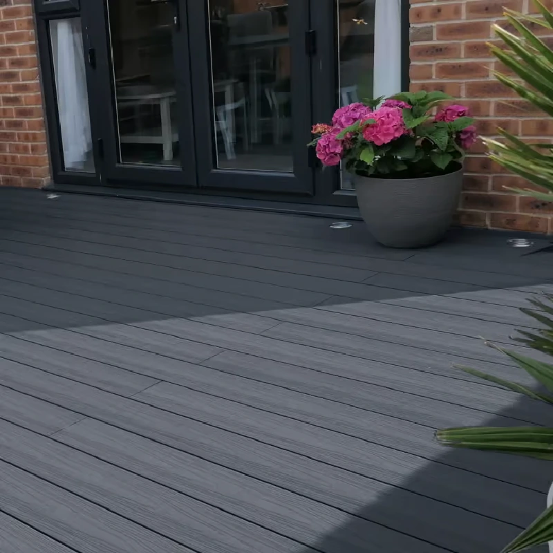 Dark grey composite decking near patio doors and plant.