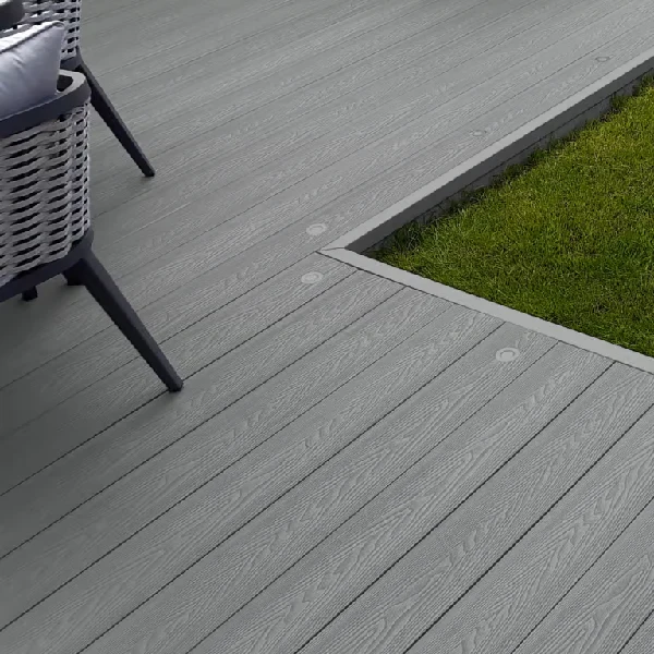 Grey composite decking next to grass with chair leg.