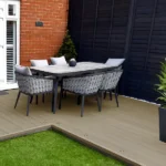 Outdoor dining set on composite decking and grass.